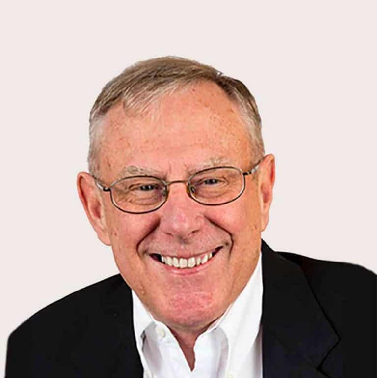 Smiling senior man in glasses and suit, professional portrait.
