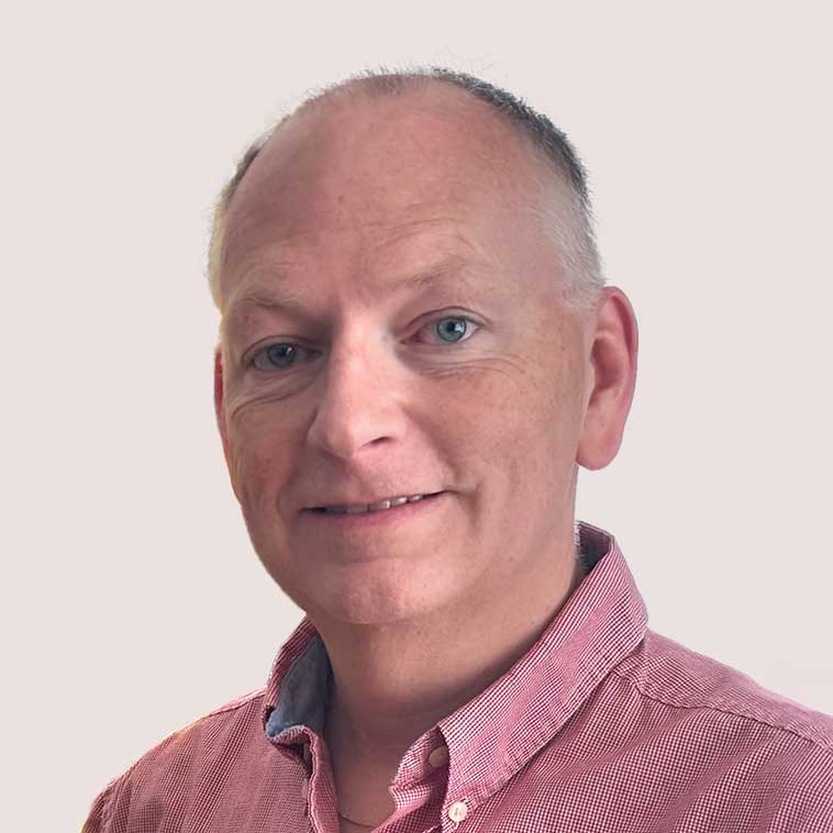 Portrait of a middle-aged man with short light hair and blue eyes, wearing a pink shirt.