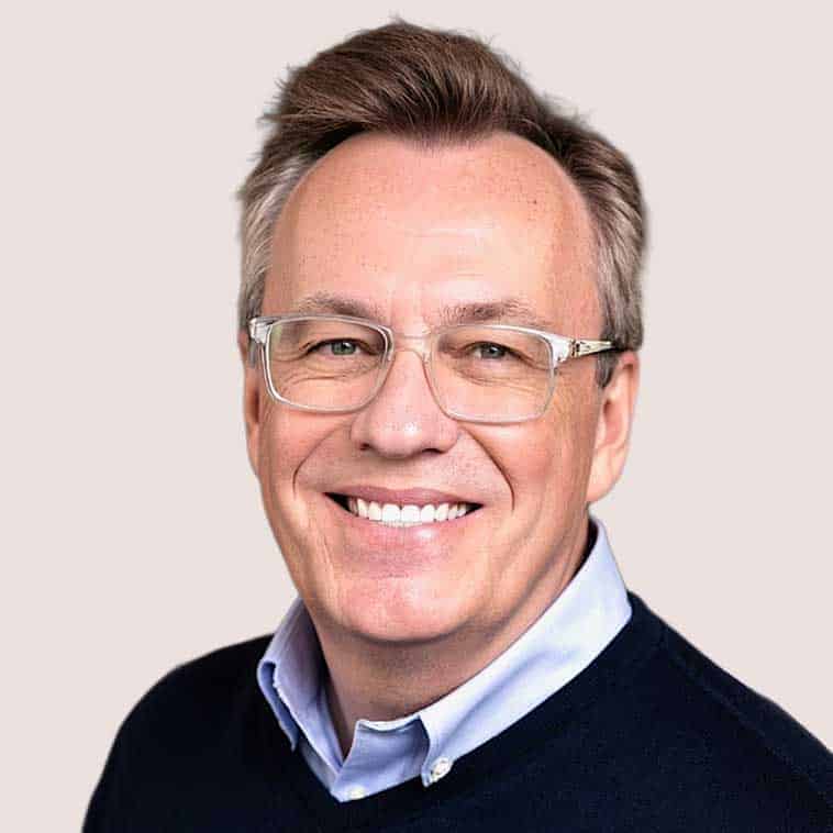 Professional portrait of a smiling man with glasses, business attire.